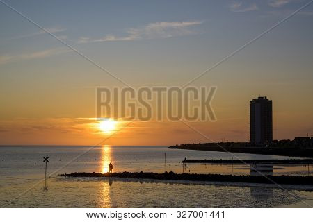 Skyscraper And Beach On The Coast Of The North Sea At Sunset In Buesum, Germany, Reflections And Lar