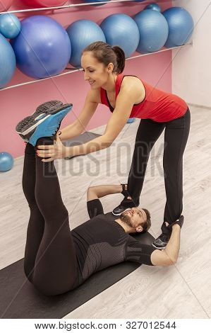 Young Man Helped By His Coach Doing Stretching Exrcises In A Gym.