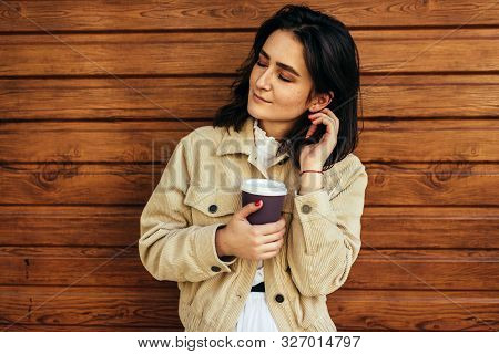 Beautiful Brunette Woman Holds Disposable Cup Of Coffee In The City Street. Happy Female Takeaway Co