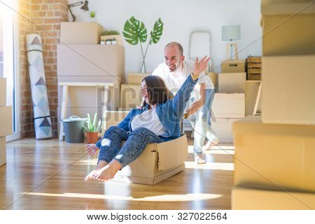 Funny and crazy couple having fun riding a cardboad box as a car, smiling happy and lauging at new home