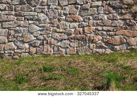 The Lower Part Of The Fortress Wall Is Made Of Gray And Pink Stones. In The Lower Part There Is An E