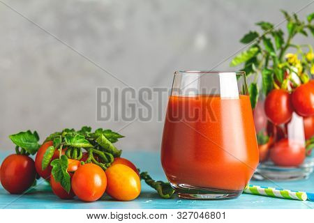 Glass Of Fresh Delicious Jummy Red Tomato Juice And Fresh Tomatoes On Light Concrete Surface. Close