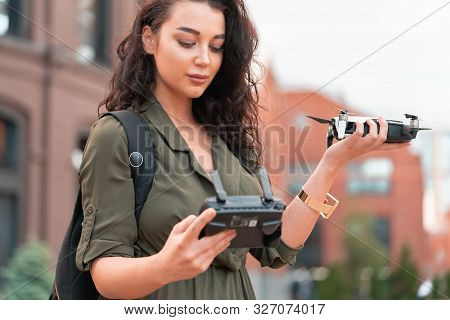 Young Beautiful Woman Launching Drone Quadcopter At Urban Background. Cityscape. Modern Device.