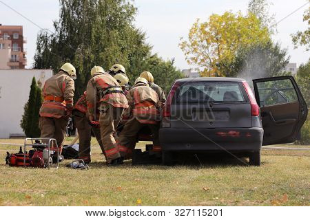 Firefighters Participate In A Training Where They Extinguish Fire From A Car Crashed Into Another Ve