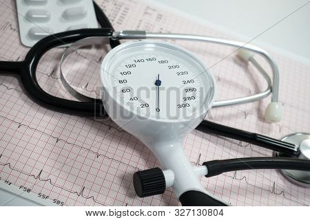 Sphygmomanometer With Aneroid Gauge, Stethoscope And Pills With Electrocardiogram Paper. Sphygmomano
