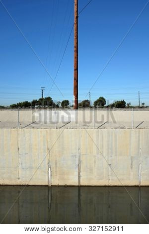 Greenville-Banning flood control channel and power poles in vertical format. The channel runs adjacent to the Santa Ana River in Costa Mesa, California.
