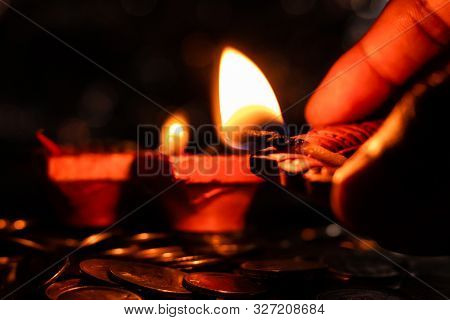 A Human Hand Holding A Glowing Lamp To Light Up The Other Earthen Lamps For Diwali Decoration