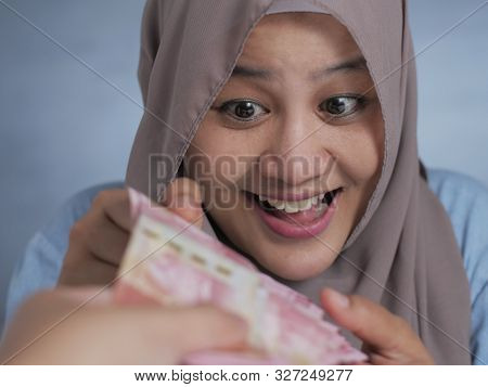 Portrait Of Indonesian Muslim Woman Receiving Rupiah Money, Smiling Joyful Gesture