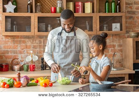 Black Smiling Girl Adding Olive Oil To Veggies Salad, Dad Mixing Vegetables In Bowl, Kitchen Interio