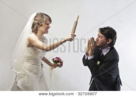 Noiva com raiva acenando ameaçando um rolo contra seu marido