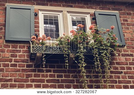 Window In A Brick Wall With Pink Flowers On A Windowsill