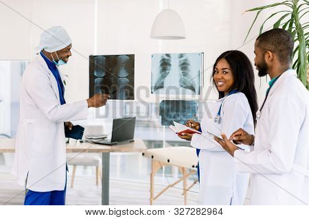 Healthcare, Medical: Group Of African Doctors Discuss And Looking X-ray In A Clinic Or Hospital. Afr