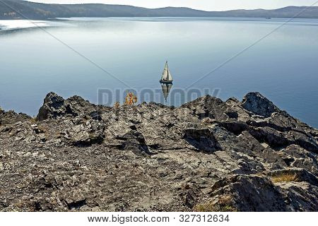 Sailing Boat On The Calm Lake Turgoyak, View From The Rocky Shore In Autumn, Southern Urals