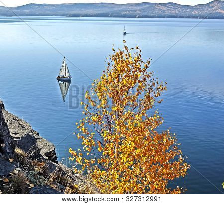 Sailing Boat On The Calm Lake Turgoyak, View From The Rocky Shore In Autumn, Southern Urals, The Lak