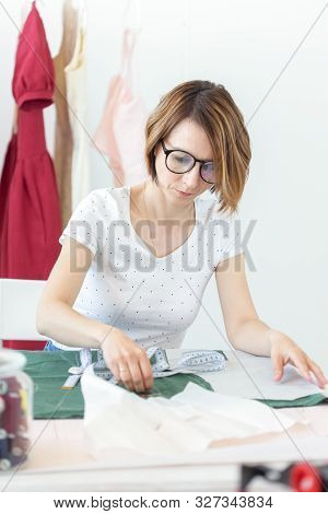 Young Pretty Girl Student Study At A Clothes Designer In College And Does Her First Thesis Sitting A