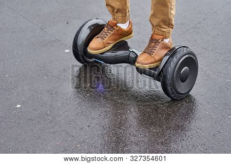 Man Using Hoverboard On Asphalt Road, Close Up. Feet On Electrical Scooter Outdoor