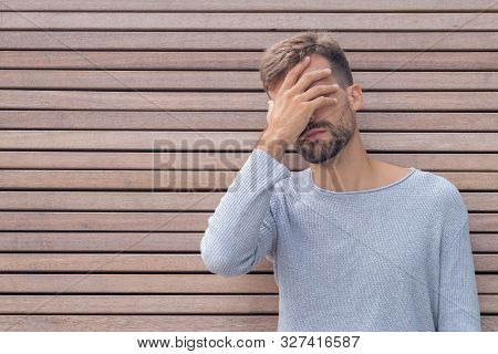 Facepalm. Ashamed Embarrassed Man Covering His Face. Young Guy On Wooden Wall Background With Copy S