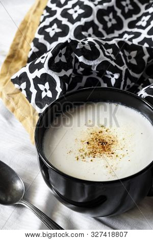 Cauliflower Soup (creme Du Barry) In Black Bowl On White Background With Black And White Cloth