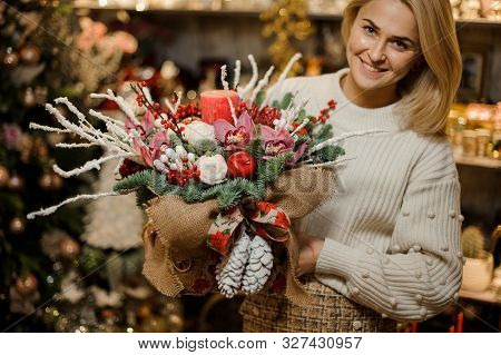 Smiling Woman Holding A Christmas Composition With Pink Orchids, White Roses, Fir-tree Branches, Red