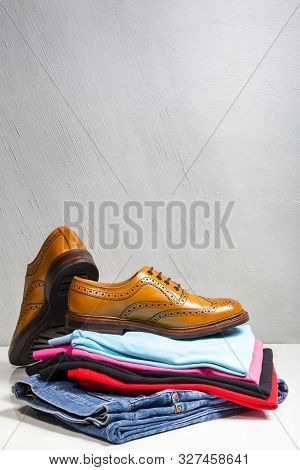 Pair Of Male Full Brogued Tan Oxford Shoes Placed On Top Of Heap Of Clothing. Vertical Image Composi
