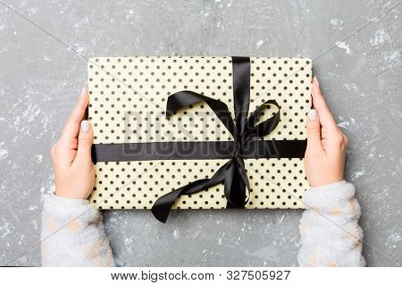 Top View Woman Hands Holding Present Box With Colored Bow On Gray Cement Wooden Background With Copy