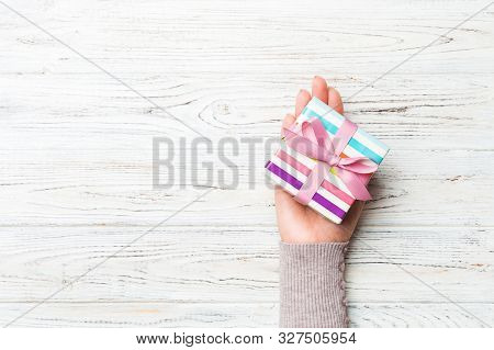 Top View Woman Hands Holding Present Box With Colored Bow On White Rustic Wooden Background With Cop