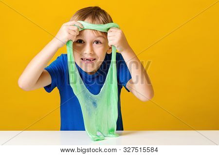 Cute Little Boy Looking Through Hole In A Slime. Happy Kid Plays With Slime. Happy Childhood. Trendy