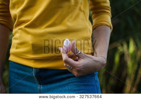 Adult Girl In Yellow Shirt And Blue Jeans Is Holding Pink Quartz Yoni Egg For Vumfit, Imbuilding Or 