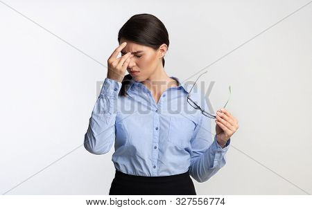 Eyes Fatigue. Overworked Businesswoman Massaging Nosebridge Holding Eyeglasses Standing Over White B