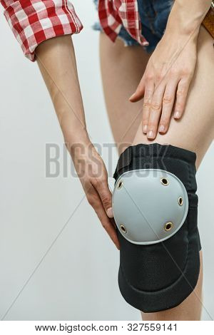 Unrecognizable Woman Wearing And Adjusting Her Safety Knee Protectors Pads. Safe Workwear During Con