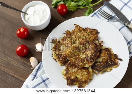 Few Pancakes Of Zucchini On The Plate, Sour Cream With Herbs, Poltice Wooden Background, Fresh Cherr