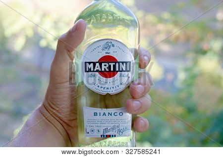 Kharkov, Ukraine - September 23, 2019: Bottle Of Vermouth Martini Rossi In Male Hand On A Green Tree