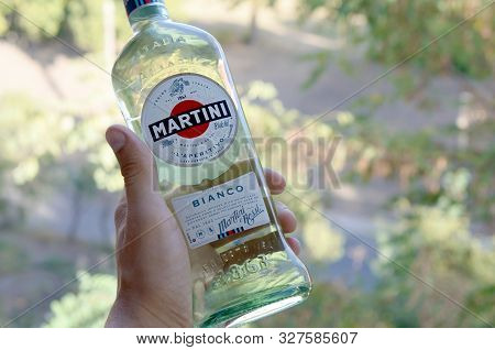 Kharkov, Ukraine - September 23, 2019: Bottle Of Vermouth Martini Rossi In Male Hand On A Green Tree