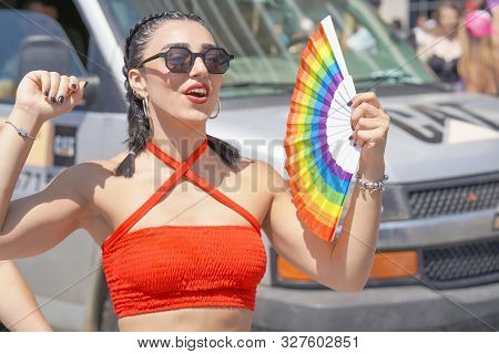 Portrait Of Happy Lesbian Walking In The Gay Pride Parade. Parade Of Tolerance. Rainbow Flags At Gay