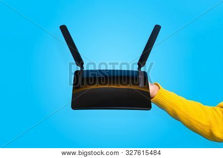 Black Wifi Router On Hand Over Blue Background