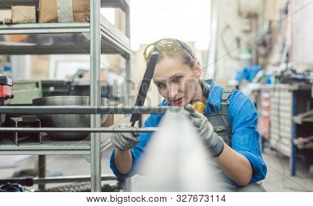 Woman metalworker checking the accuracy of her work holding steel file in her hand