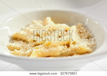 Delicious penne four cheeses close up. Traditional italian cuisine restaurant menu item. Tasty pasta isolated on white background. Macaroni dish with formaggi, mozzarella, gorgonzola and fontina