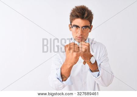 Young handsome sciencist man wearing glasses and coat over isolated white background Ready to fight with fist defense gesture, angry and upset face, afraid of problem
