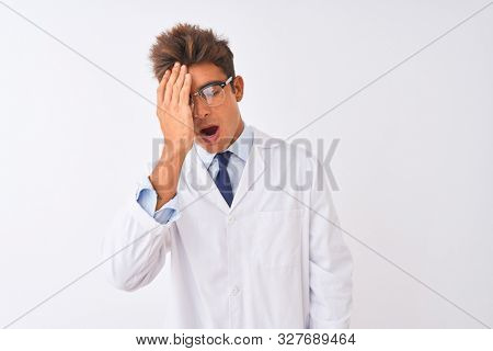 Young handsome sciencist man wearing glasses and coat over isolated white background Yawning tired covering half face, eye and mouth with hand. Face hurts in pain.