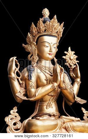 The Gilded Four-armed Form Of Avalokiteshvara Made Of Metal Isolated On Black Background. Executed I