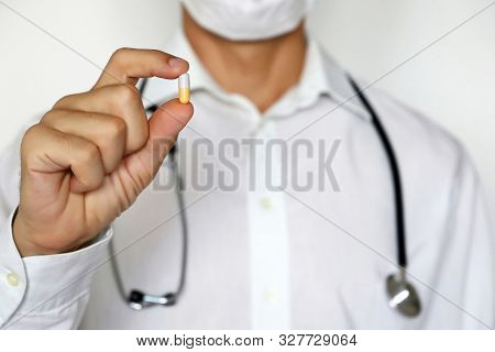 Doctor Holding Pill, Male Hand With Medication In Capsule Close-up. Physician In Medical Mask With T