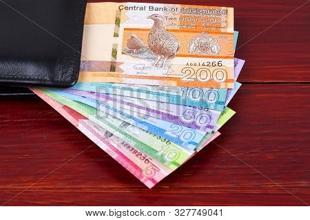 Gambian Dalasi In The Black Wallet On A Wooden Background