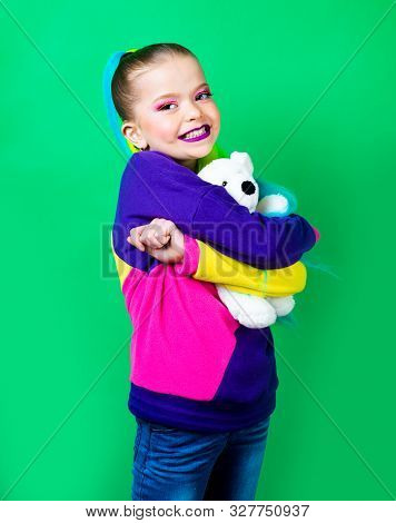 Smiling Little Girl With Colored Hair Embracing Teddy Bear. The Concept Of Childrens Attachments.tex