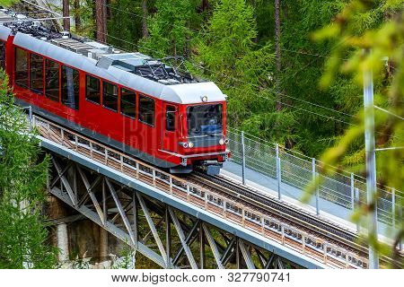 Zermatt, Switzerland. Gornergrat Red Tourist Train Close-up On The Bridge In Swiss Alps