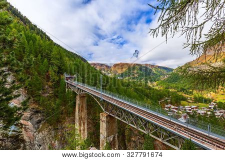 Zermatt, Switzerland. Gornergrat Red Tourist Train On The Bridge And Matterhorn Panorama In Swiss Al