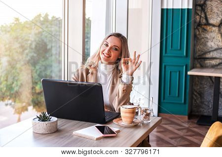 Beautiful Business Woman Sitting In Cafe Andworking. There Are Laptop, Smartphone And Cup Of Coffee.