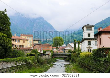 Wonderful Italian Mandello Landscape With Lovely Houses, Trees And Mountains In Background.
