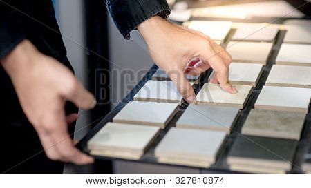 Male Architect Or Interior Designer Hand Choosing Ceramic Texture Sample From Swatch Board In Design