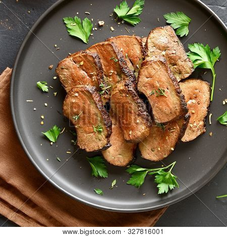 Close Up Of Grilled Sliced Beef Liver On Plate Over Black Stone Background. Cooked Liver(offal) From