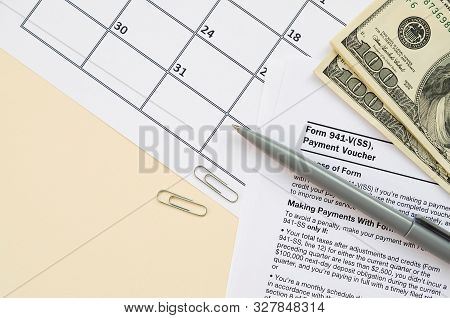 Irs Form 941-v Payment Voucher Blank Lies With Pen And Many Hundred Dollar Bills On Calendar Page